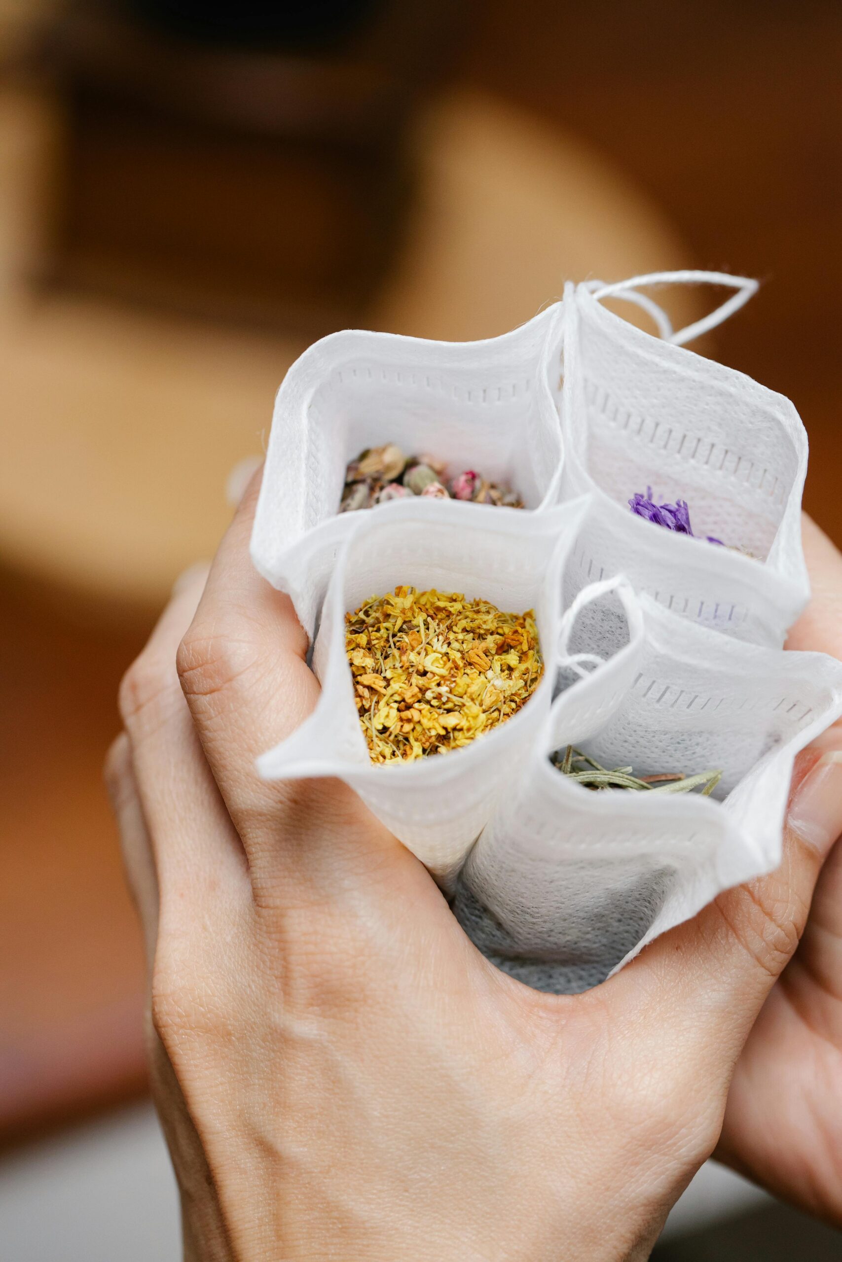 Close-up of hands holding various herbal tea bags filled with colorful ingredients.